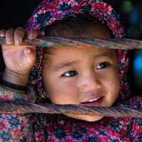 A girl smiles through a school window in Nagarkot, Nepal. © Kertu | Shutterstock 